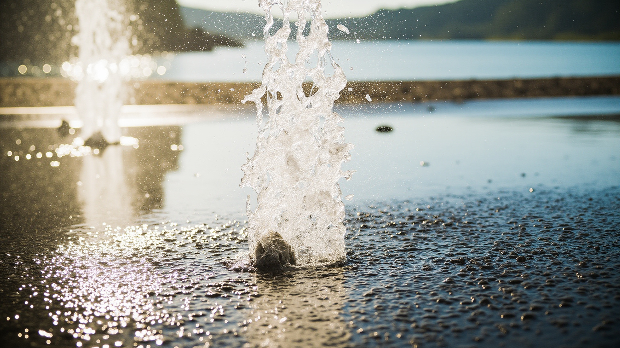 splashpads featured surrey Best Splash Pads and Outdoor Pools in Surrey, BC: A Summer Guide Water jet spraying upward from a splash pad nozzle on wet dark pavement, sunlit water droplets catching light in Surrey BC